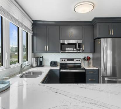 Stylish kitchen with quartz countertops, stainless steel appliances, and navy cabinetry—enjoy cooking with a view through the bright corner window.
