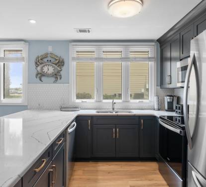 Bright and modern kitchen with sleek navy cabinets, stainless appliances, and quartz countertops—fully equipped for all your cooking needs.