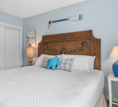 Peaceful guest bedroom with king bed, coastal accents, and crisp white bedding—designed for restful nights in a charming beachside setting.