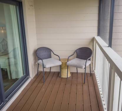 Cozy balcony nook with cushioned chairs and a side table—an ideal spot for quiet mornings, reading, or unwinding after a beach day.