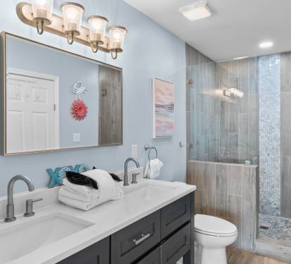 Elegant en-suite bathroom with double vanity, quartz countertop, and a spa-style walk-in shower—designed with coastal charm and modern finishes for a refreshing retreat.