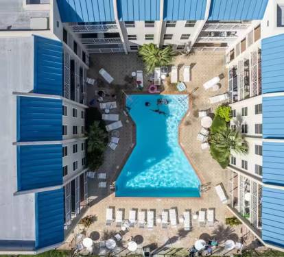 Resort-style pool oasis with loungers, palms & sunshine—perfect for relaxing just steps from your door.