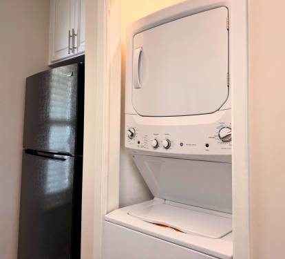 A stacked washer-dryer unit nestles conveniently in the kitchen alcove, with a sleek refrigerator nearby—so you can keep essentials close and your wardrobe fresh throughout your stay.
