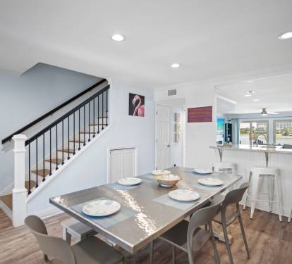 Chic dining area with a sleek metal-top table, bench and chair seating, and warm LVP wood floors. Open layout connects to kitchen and living space.