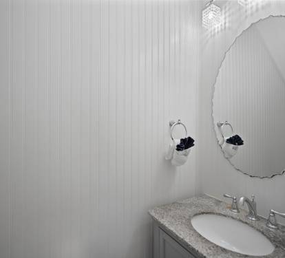 Chic half bathroom with white beadboard walls and a granite countertop. Features sleek chrome fixtures and a modern light fixture for a clean, coastal look.