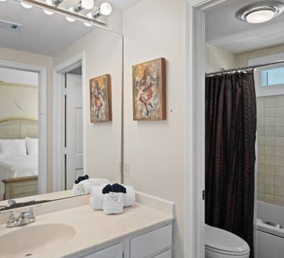 Guest bathroom with a spacious vanity, large mirror, and bright lighting. Features a separate toilet and shower area.