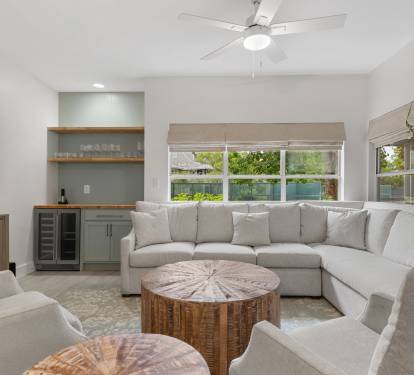 Light-filled and inviting, this living space features a roomy sectional, rustic textures, and built-in bar.