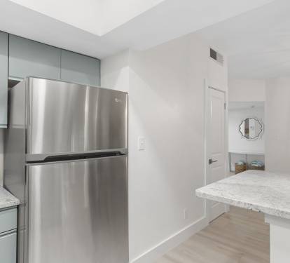 This kitchen nook features wood cabinetry, granite counters, and a sleek stainless-steel refrigerator.