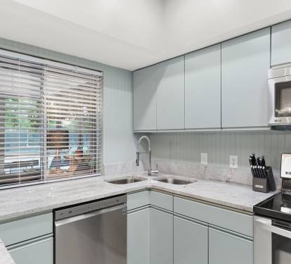 This bright kitchen features sleek wood cabinetry, granite countertops, and stainless-steel appliances.