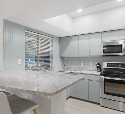 This modern kitchen shines with wood cabinetry, granite counters, and stainless-steel appliances.