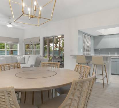 This airy dining space blends natural textures with soft lighting and an easy flow into the kitchen and patio.