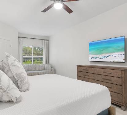 This spacious bedroom features a king bed, queen-size pullout sofa, flat-screen TV, and relaxing coastal style.