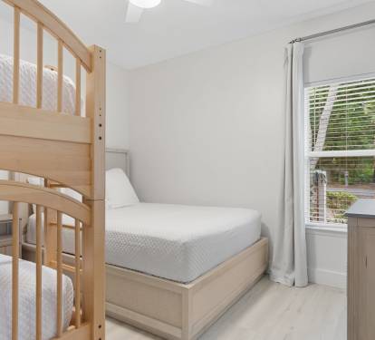 This light-filled guest room offers a queen bed and twin bunks, creating a perfect space for family comfort.