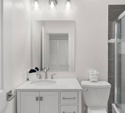 This modern guest bathroom features a crisp white vanity, sleek fixtures, and a tiled tub/shower combo.