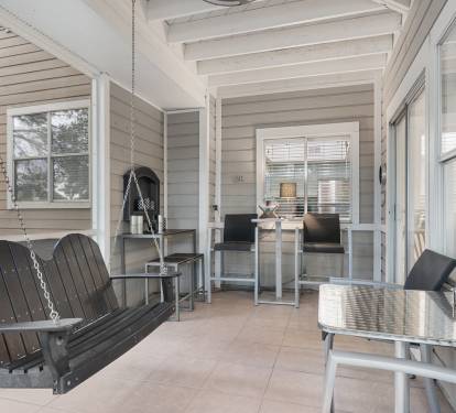 This screened-in porch offers a relaxing retreat with a classic swing, dining area, and charming coastal touches.