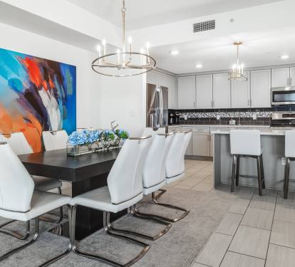 Gather around your elegant dining table with modern white chairs, while vibrant artwork energizes your open-concept kitchen space.