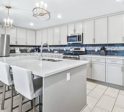 Your gourmet kitchen features sleek white cabinetry, granite countertops, and modern stainless appliances - perfect for preparing memorable meals during your stay.