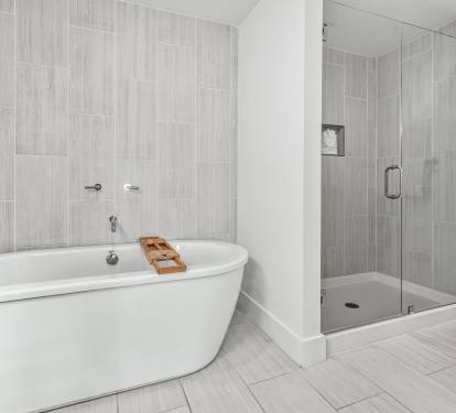 Unwind in your spa-like bathroom with a luxurious soaking tub and modern glass shower, featuring elegant tile work throughout.