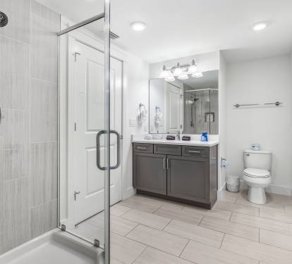 Step into your sleek modern bathroom with spacious glass-enclosed shower and ample vanity space for your morning routine.