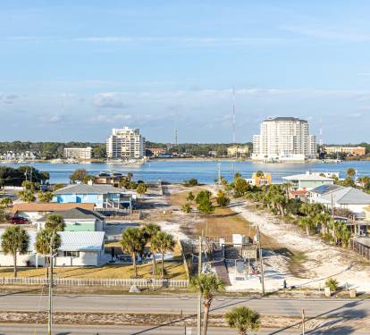 Coastal community featuring waterfront homes, high-rise buildings, and marina access across the bay.