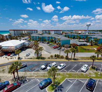 Aerial view showcasing the beachfront property location with convenient parking, nearby coastal lodging, and a water tower marking the surrounding neighborhood.