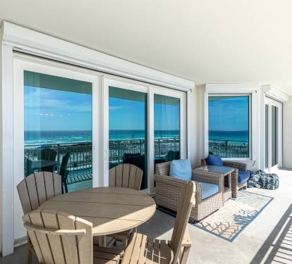 Your private covered terrace opens to stunning ocean views, complete with dining table and lounge seating for seaside relaxation.