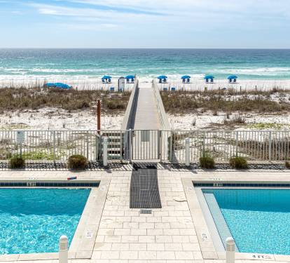 Pristine beachfront resort with swimming pool, boardwalk access to white sand beach and emerald waters.