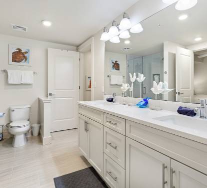 Unwind in your spacious master bathroom with dual vanities, gleaming countertops, and a refreshing glass-enclosed shower after your beach adventures.
