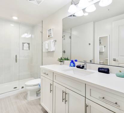 Refresh in your spacious modern bathroom with a glass-enclosed shower, dual vanities, and pristine white finishes that create a spa-like retreat.