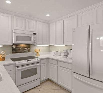 Fully equipped kitchen features white cabinets, granite countertops, and all essential appliances for preparing your favorite meals during your stay.