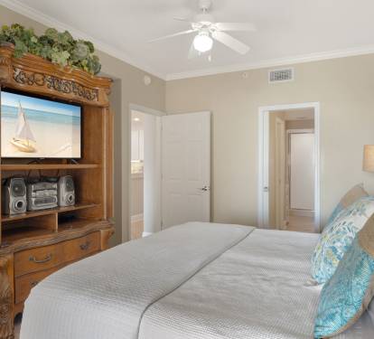 Relax in the peaceful bedroom with coastal charm, featuring a comfortable bed and entertainment center for cozy evenings in.