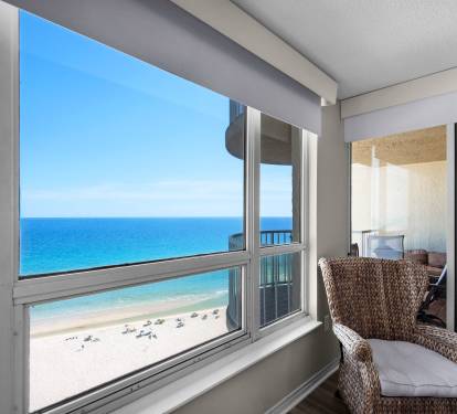Stunning beachfront views frame your private sanctuary, where turquoise waves meet soft sand and a cozy woven chair invites you to relax