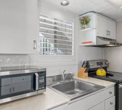 The kitchen features everything needed for easy meal prep, including a stovetop, microwave, coffee maker, and convenient counter space. Bright coastal touches and an open layout make the space feel comfortable and inviting.
