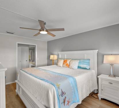 The primary bedroom offers a comfortable king bed, coastal-inspired décor, and a peaceful atmosphere perfect for relaxing after a day at the beach. A bright and inviting retreat designed for comfort and rest.