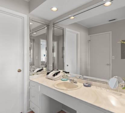 The dressing area features a spacious vanity with ample counter space, bright lighting, and large mirrors, creating the perfect spot to get ready for a day at the beach or an evening out.