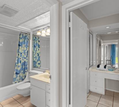 Bright and spacious bathroom with a tub/shower combo and cheerful blue-accented decor, plus a separate vanity area for your morning routine.