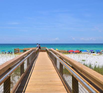 Scenic boardwalk at Sandpiper Cove Resort leading to a private, sugar-white sand beach with sweeping views of emerald Gulf waters and a relaxed, coastal atmosphere.