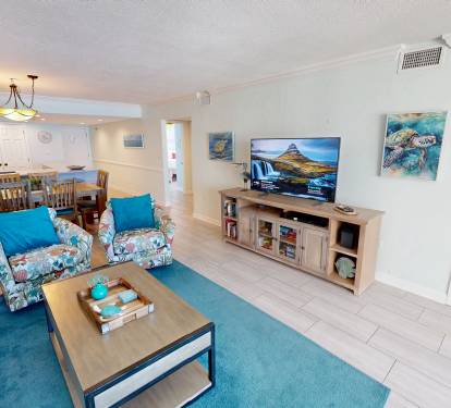 Relax in your bright, coastal-themed living space where ocean artwork and turquoise accents create the perfect beach vibe for your getaway.