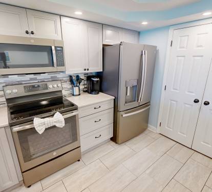 Your fully equipped kitchen features pristine white cabinets, stainless steel appliances, and a stylish tile backsplash—perfect for whipping up delicious meals during your stay.