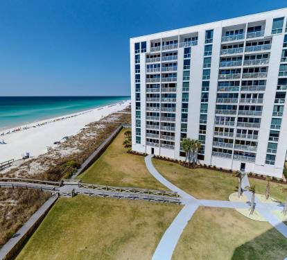 Stunning beachfront high-rise property with direct beach access via wooden boardwalk and manicured grounds.