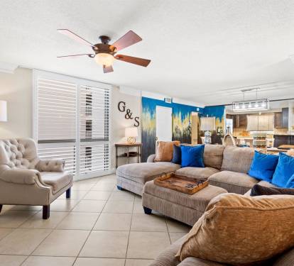 Unwind in your spacious living room featuring plush seating and vibrant coastal artwork that brings beachside tranquility indoors.