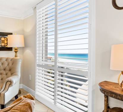 Sink into your private seating area where ocean breezes drift through elegant blinds, framing stunning sea views.