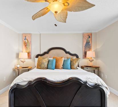 Unwind in this elegant bedroom featuring a plush bed with tropical-inspired linens and charming peacock artwork that sets a serene tone.