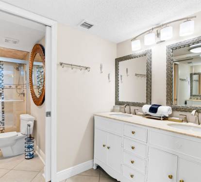 Your spacious bathroom features dual vanities, elegant mirrors, and a stunning mosaic tile shower—perfect for refreshing after beach adventures.