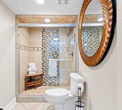 Refresh in your beautifully tiled bathroom featuring a spacious walk-in shower with stunning mosaic accents and convenient bench seating.