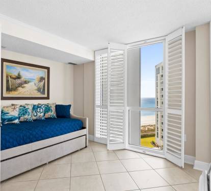 Wake up to stunning ocean views from your cozy daybed, where coastal breezes drift through plantation shutters into your serene retreat.