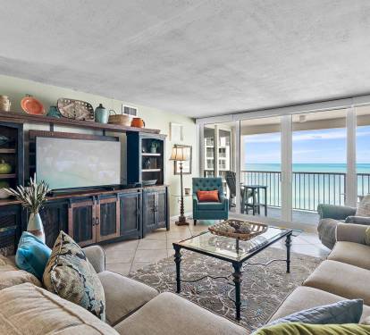 Sink into plush sofas while ocean waves dance beyond your floor-to-ceiling windows in this elegant beachfront living room.