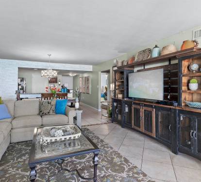 Relax in your spacious living area with plush sectional seating, entertainment center, and open layout flowing to the modern kitchen.