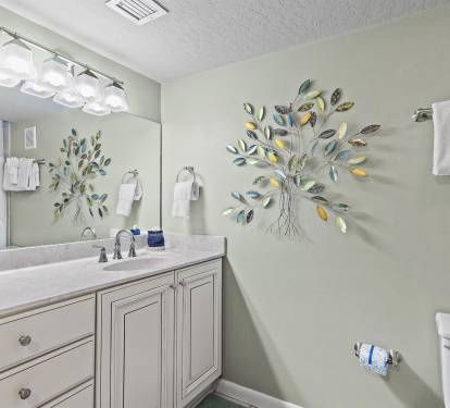Your private spa-like bathroom features elegant vanity, decorative tree art, and fluffy towels for ultimate relaxation.