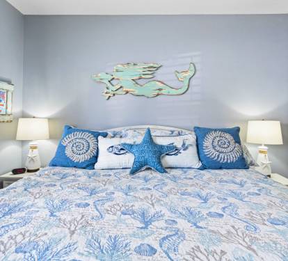 Sink into coastal comfort with ocean-themed bedding and charming mermaid wall art creating your seaside sanctuary.